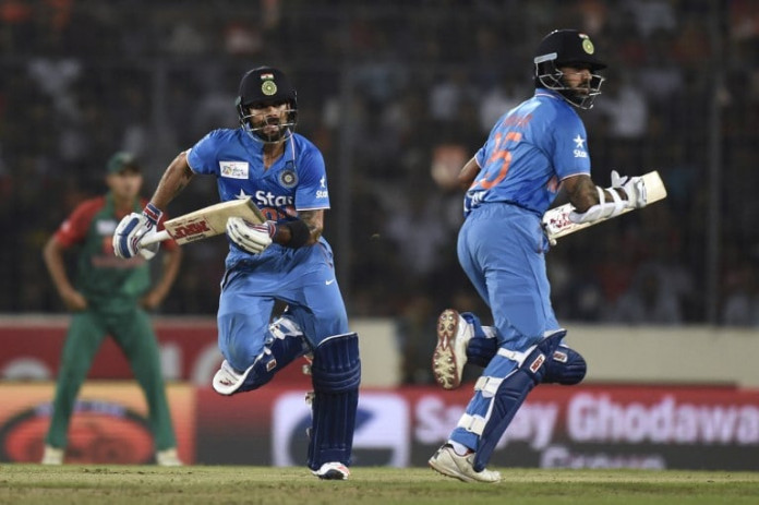 Indian cricketer Virat Kohli (L) and Shikhar Dhawan (R) run between the wickets during the Asia Cup T20 cricket tournament final match between Bangladesh and India at the Sher-e-Bangla National Cricket Stadium in Dhaka on March 6, 2016. / AFP / MUNIR UZ ZAMAN