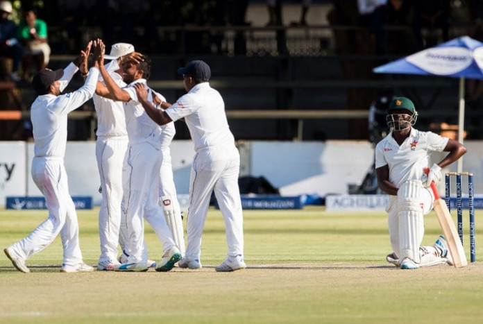 Sri Lanka's players (L) celebrate the wicket of a kneeling Donald Tiripano during the third day of the first Test match in a series of two cricket matches between Sri Lanka and Zimbabwe at the Harare Sports Club, October 31, 2016.