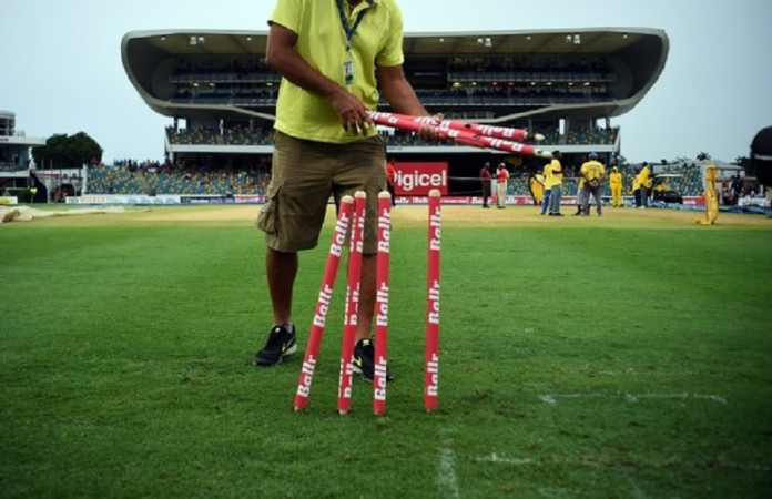 A man collects the stumps from the field after rain interrupted at the Kensington Oval stadium in Bridgetown