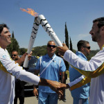 Olympic flame second torch bearer former volleyball player Giovane Gavio from Brazil passes the torch to third bearer Dimitrios Mougios as they attend the Olympic flame lighting ceremony for the Rio 2016 Olympic Games on the site of ancient Olympia